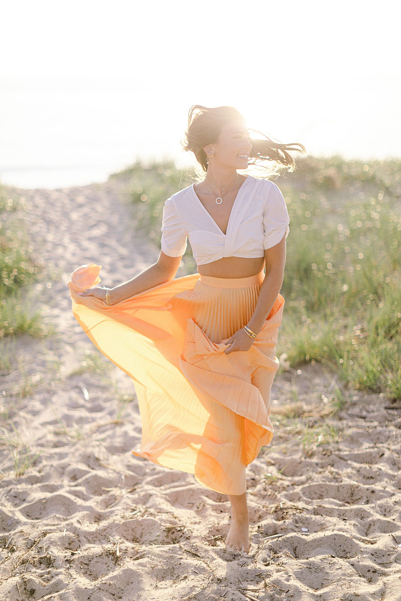 A high school senior walking in the sand dunes and twirling her yellow shirt