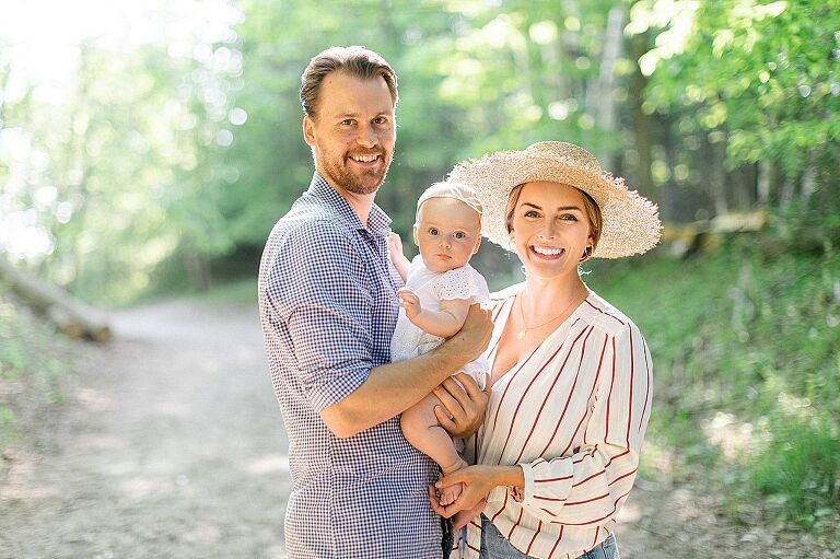 A mother, father, and their baby daughter taking portraits on a trail in the woods at Mt. McSauba in Charlevoix, Michigan