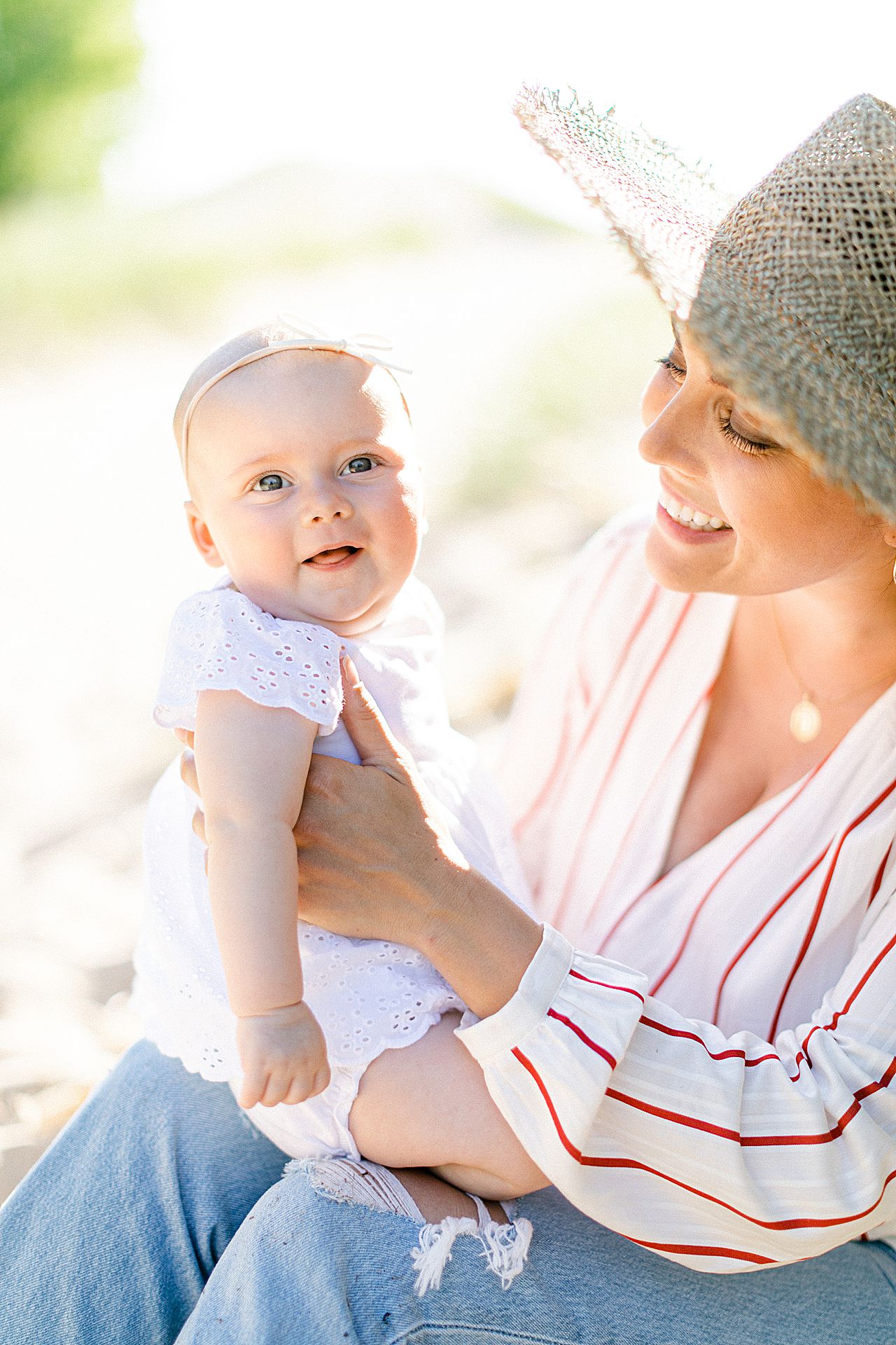 A baby girl being her by her mother and smiling in Charlevoix, Michigan