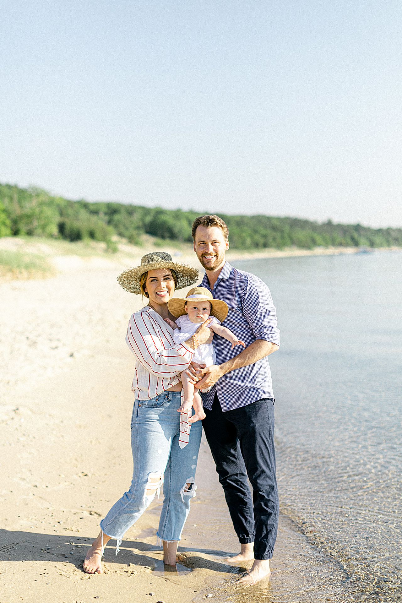 A family of 3 taking portraits along Lake Michigan in Charlevoix, Michigan