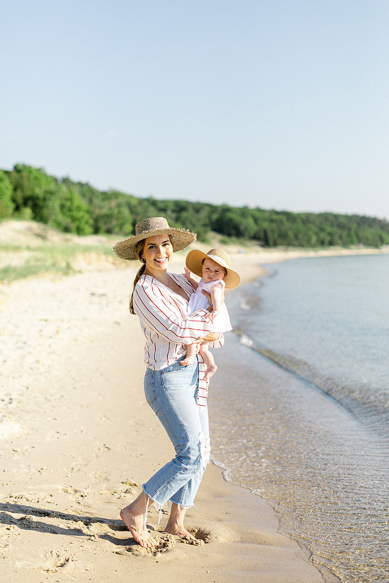 A mother holding her baby daughter by Lake Michigan on a sunny day in the summer