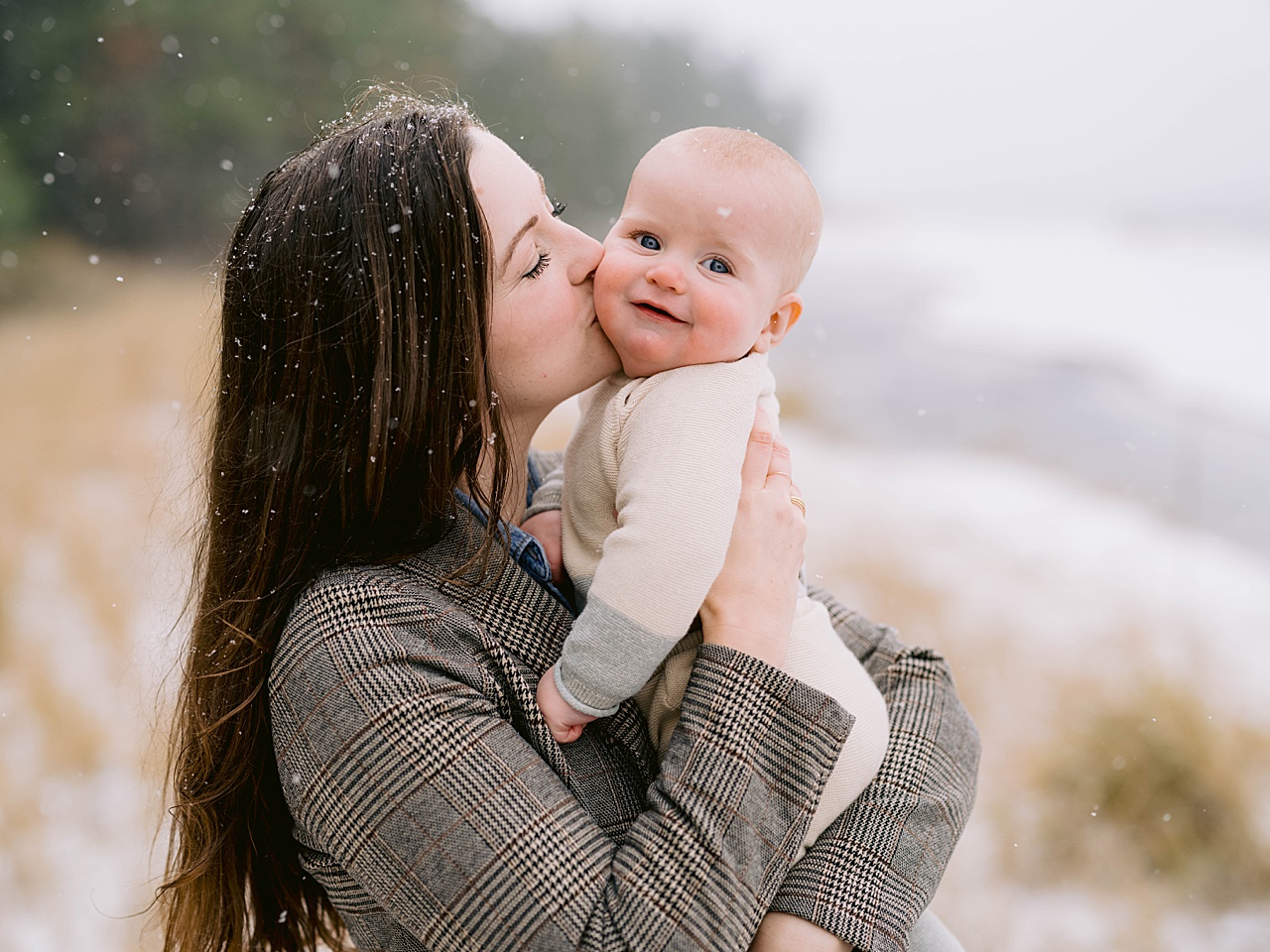 A baby being kissed on his cheek by his mother