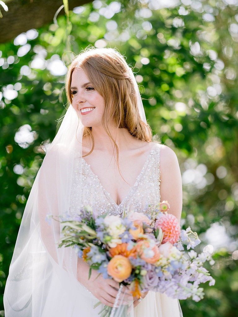 A bride smiles while looking into the distance on a brightly lit day in Michigan.
