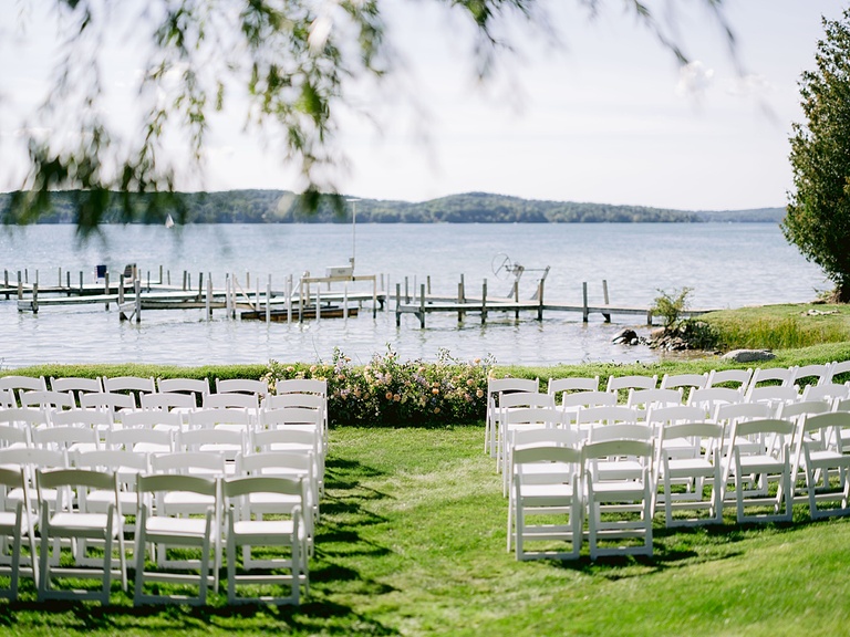 White wooden folding chairs at a ceremony spot on Walloon Lake, Michigan on a bright, sunny day.