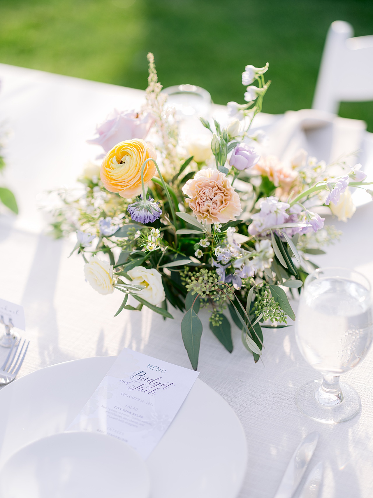 Detail shot of reception with pastel flowers, white charger, and wedding menu.