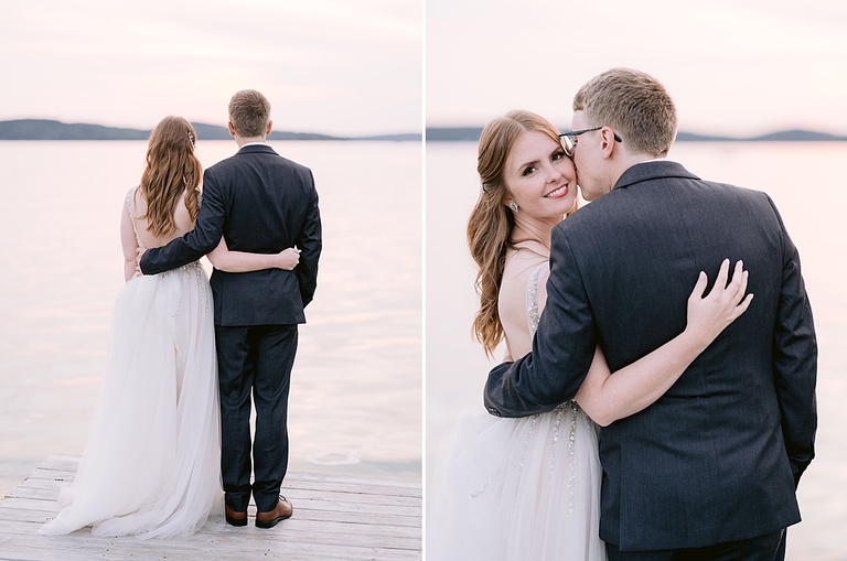 A bride and groom holding each other with a sunset lit lake in the background.