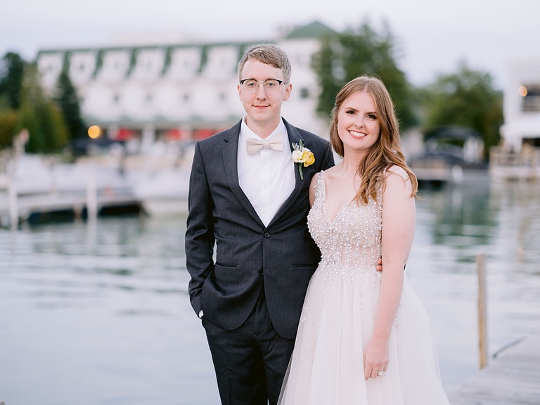Portrait of a bride and groom on a dock in front of Hotel Walloon.