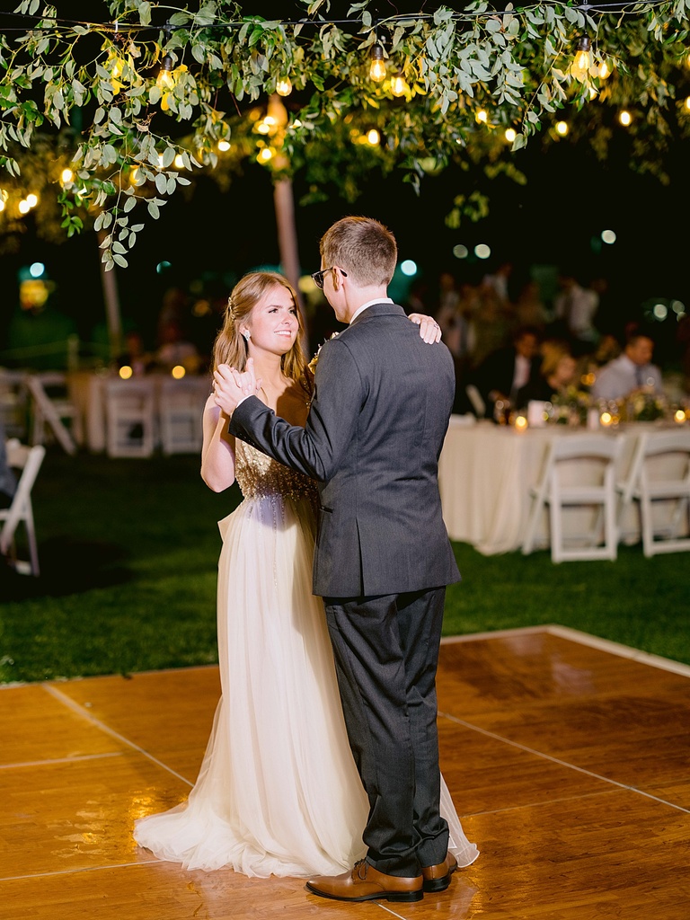 A bride and groom smiling while dancing at an outdoor reception in Michigan in the evening.