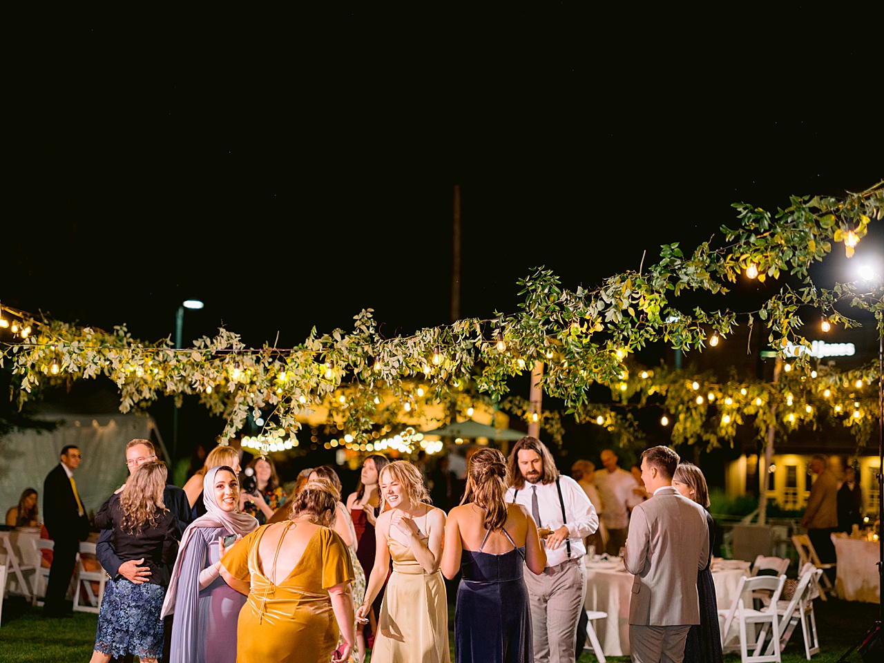 Wedding guests laughing and dancing at an outdoor reception at night in Walloon Village.