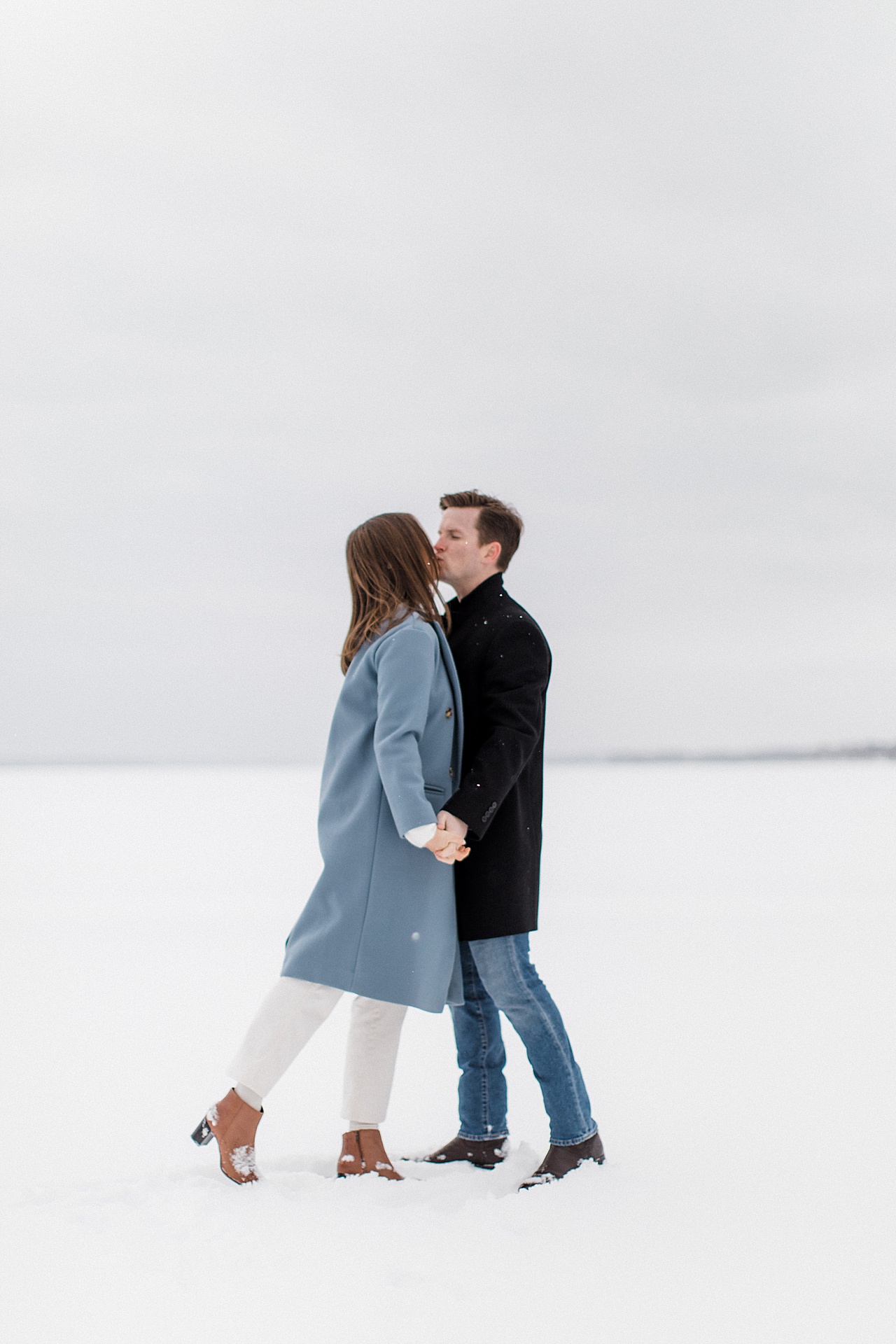 An engaged couple kissing in the winter