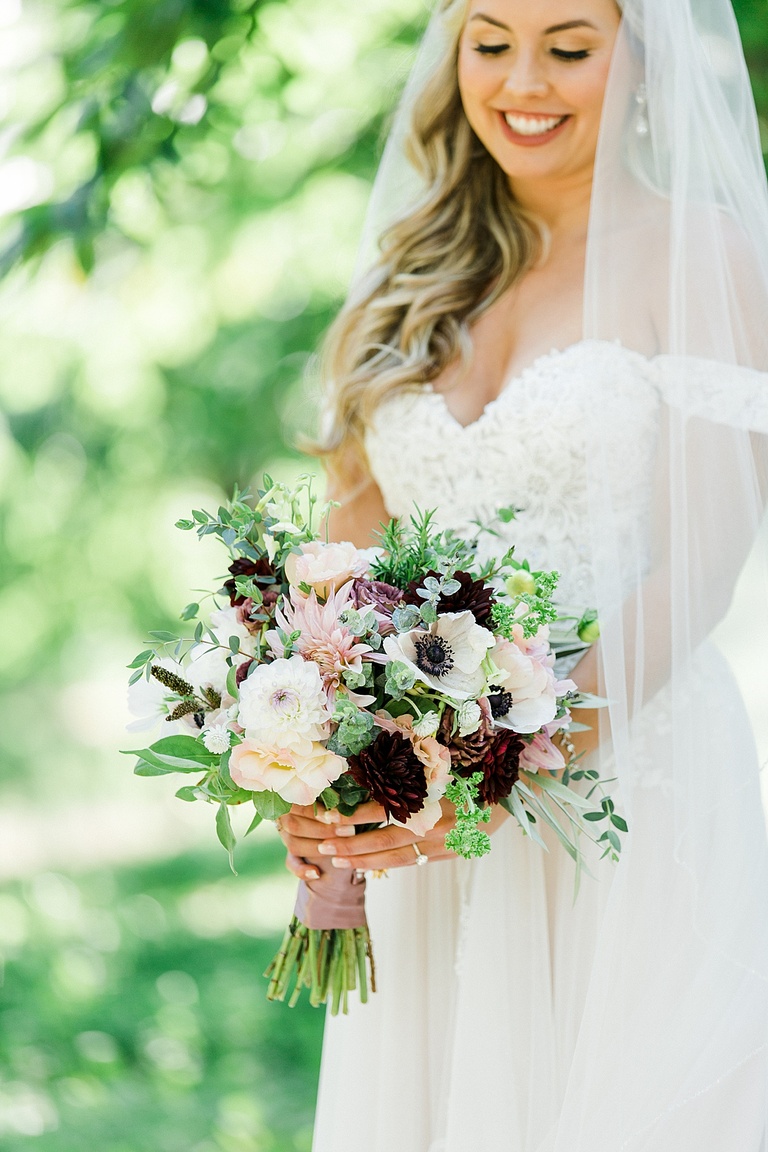 A bridal bouquet with white, pink, and burgundy flowers
