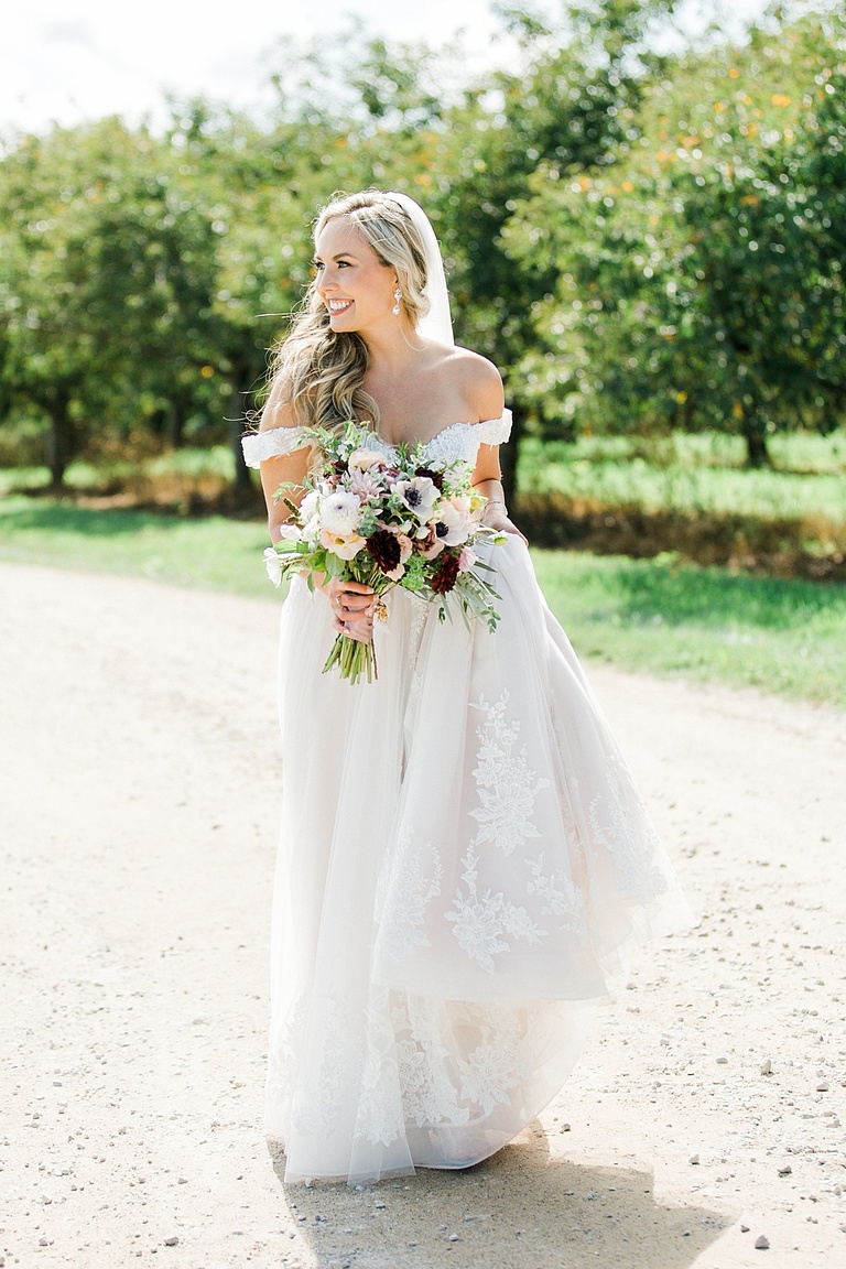 A bride standing pin the sun with a cherry orchard in the background