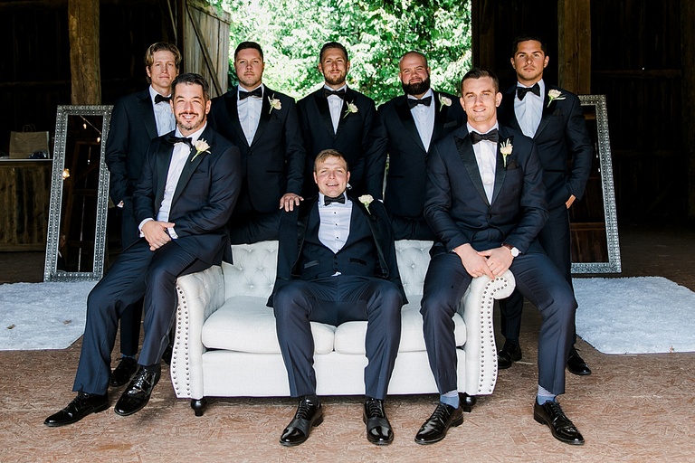 A groom and his groomsmen sitting in a barn together before the wedding ceremony