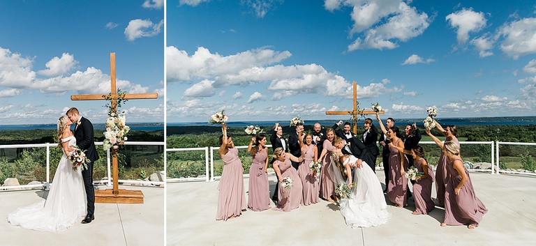 A bridal party cheering as the bride and groom kiss on a bluff overlooking Grand Traverse Bay