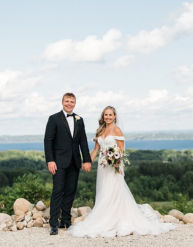 A bride and groom holding hands and smiling after their wedding ceremony on a sunny day