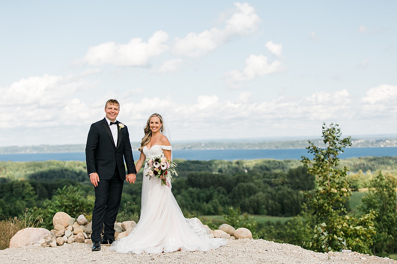 A bride and groom holding hands and smiling after their wedding ceremony on a sunny day