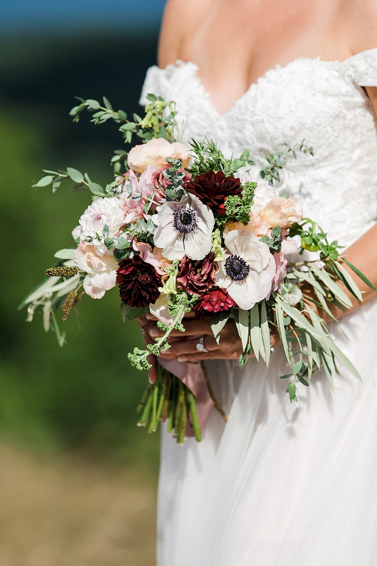 A photo of the brides bouquet in the sunlight with white and burgundy flowers