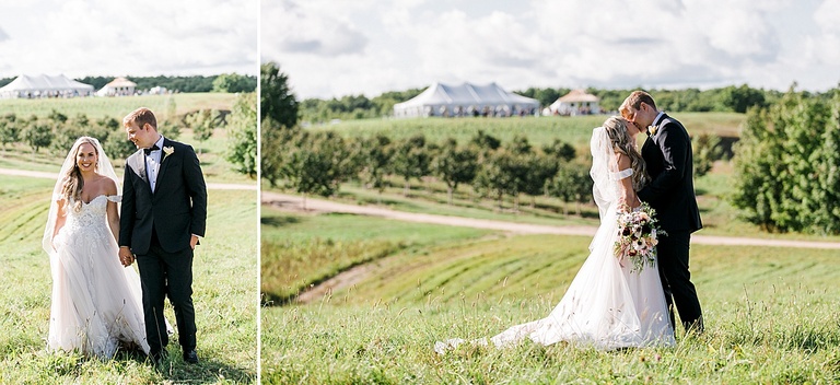 A bride and groom walking through a grassy field with the reception tent at Bay View Weddings at Gallagher Farms in the background