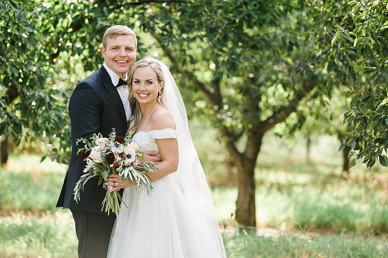 A bride and groom smiling in their wedding portraits