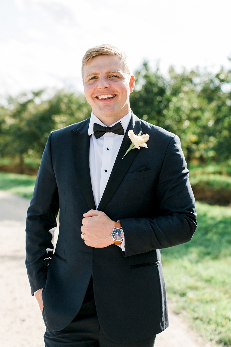 A groom smiling on his wedding day and showing off his new watch