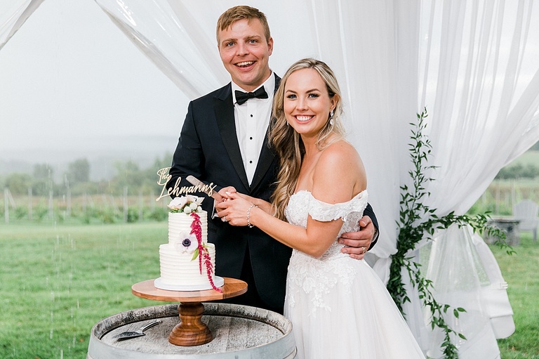A bride and groom smiling while cutting their wedding cake