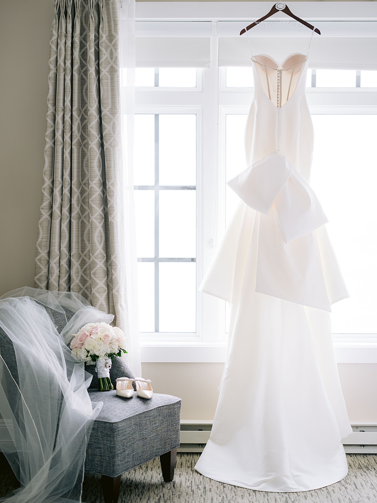Picture of a bridal gown hanging in a window in Michigan next to bridal details