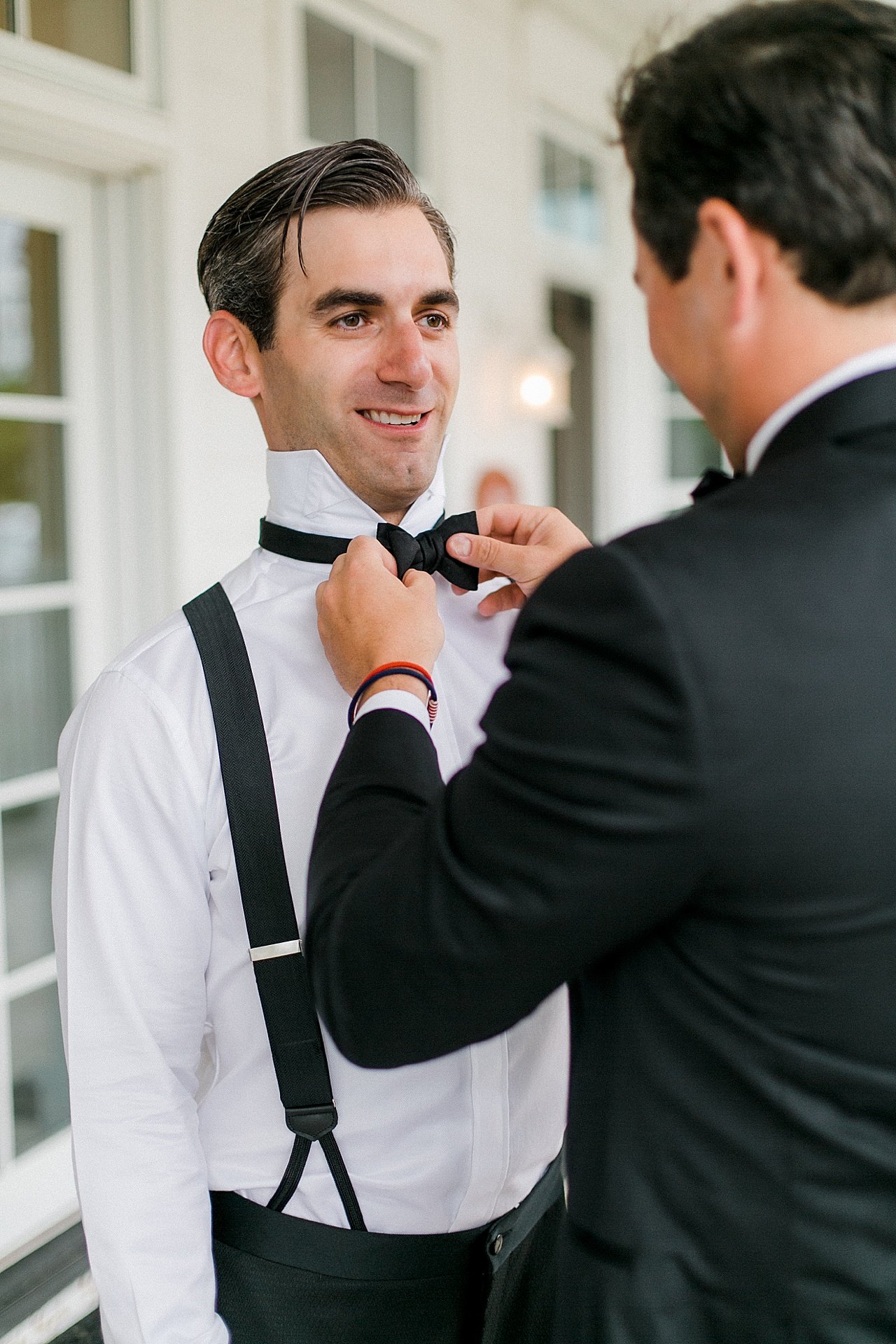 A groomsmen straightens a groom’s bow tie in Petoskey, Michigan