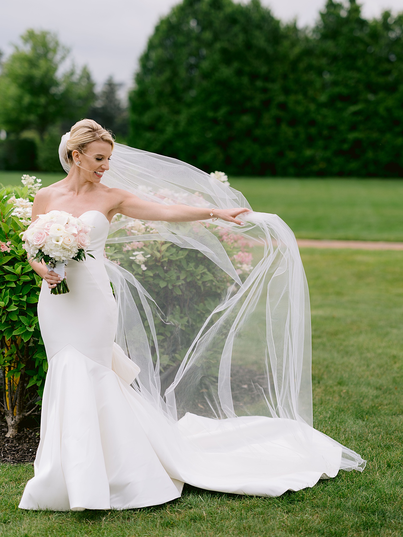 Photograph of a bride holding her veil while wind blows it in Northern Michigan