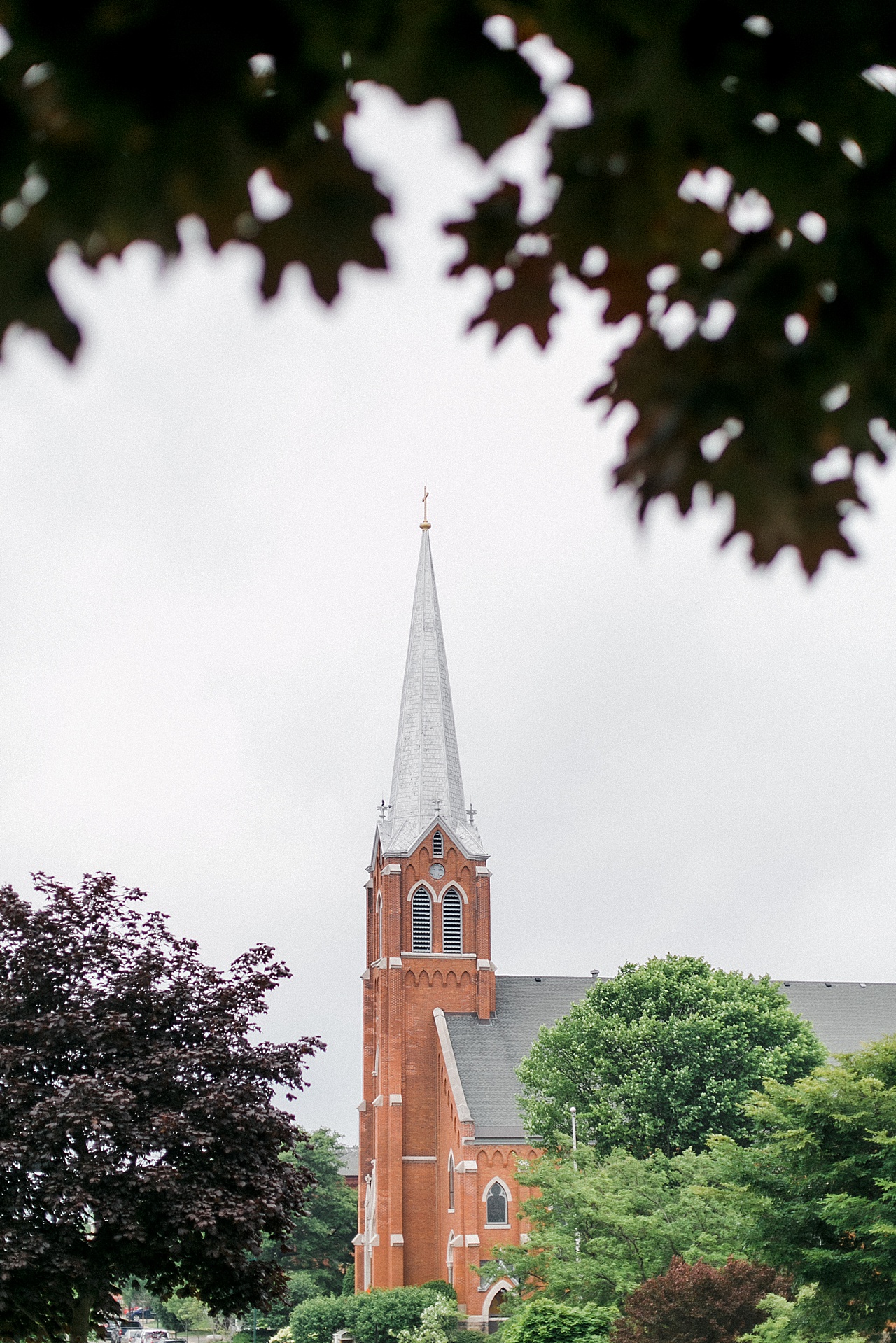A red brick church and steeple photographed through a Maple tree in Northern Michigan