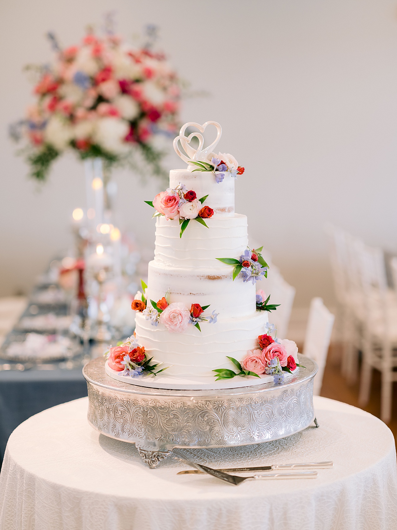A photo of a wedding cake decorated with pink roses and greenery
