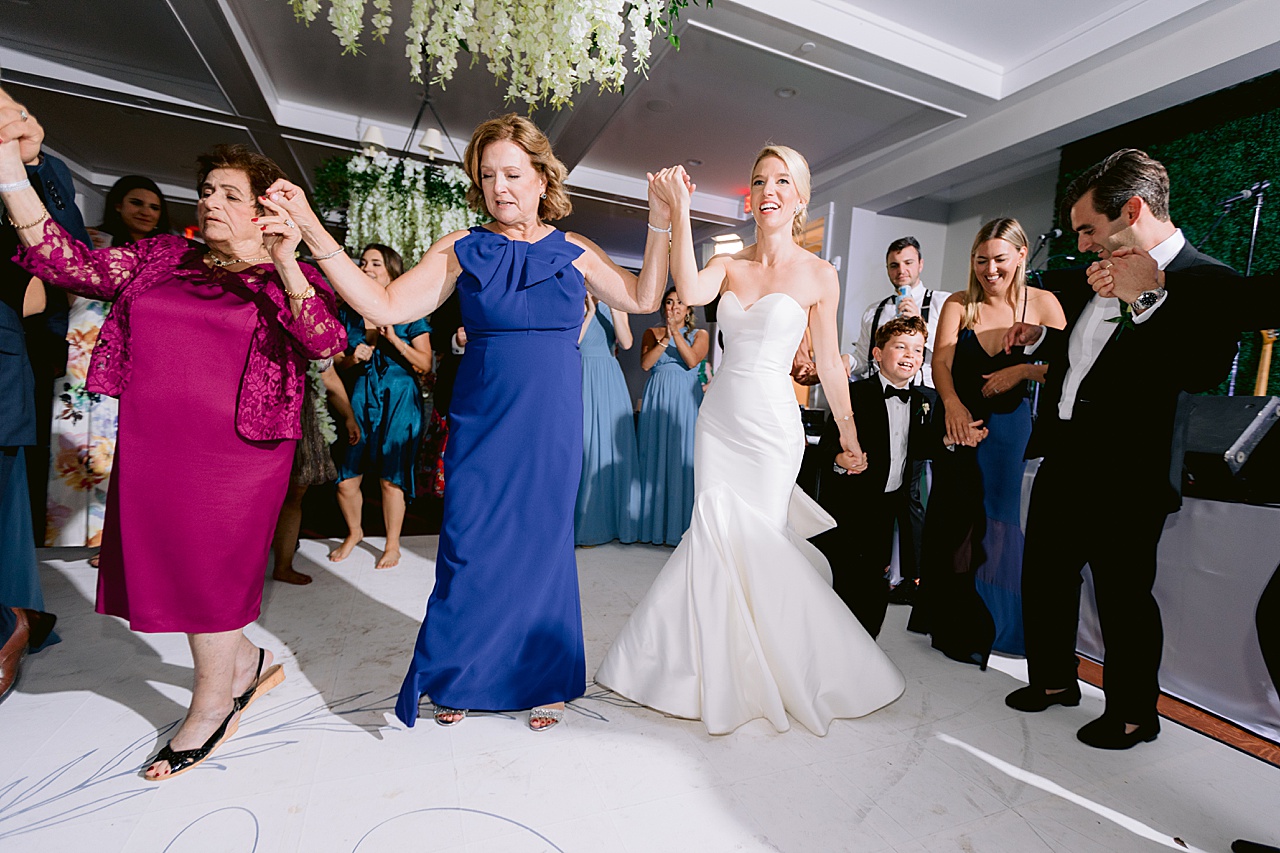 A bride and wedding guests holding hands and dancing in a line