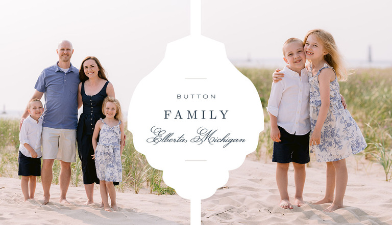 A family smiles while standing together on a sandy beach in sunny Northern Michigan