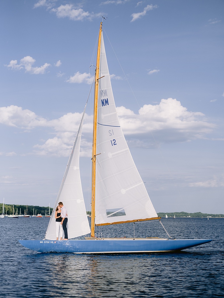 A couple kissing while sailing in Northern Michigan on a sunny day with blue skies and puffy clouds