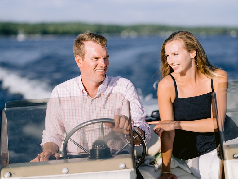 A couple looking at each other and smiling while driving a boat in Harbor Springs