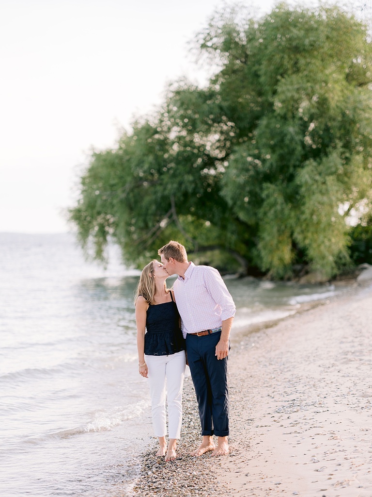 An engaged couple kissing on a beach in Michigan