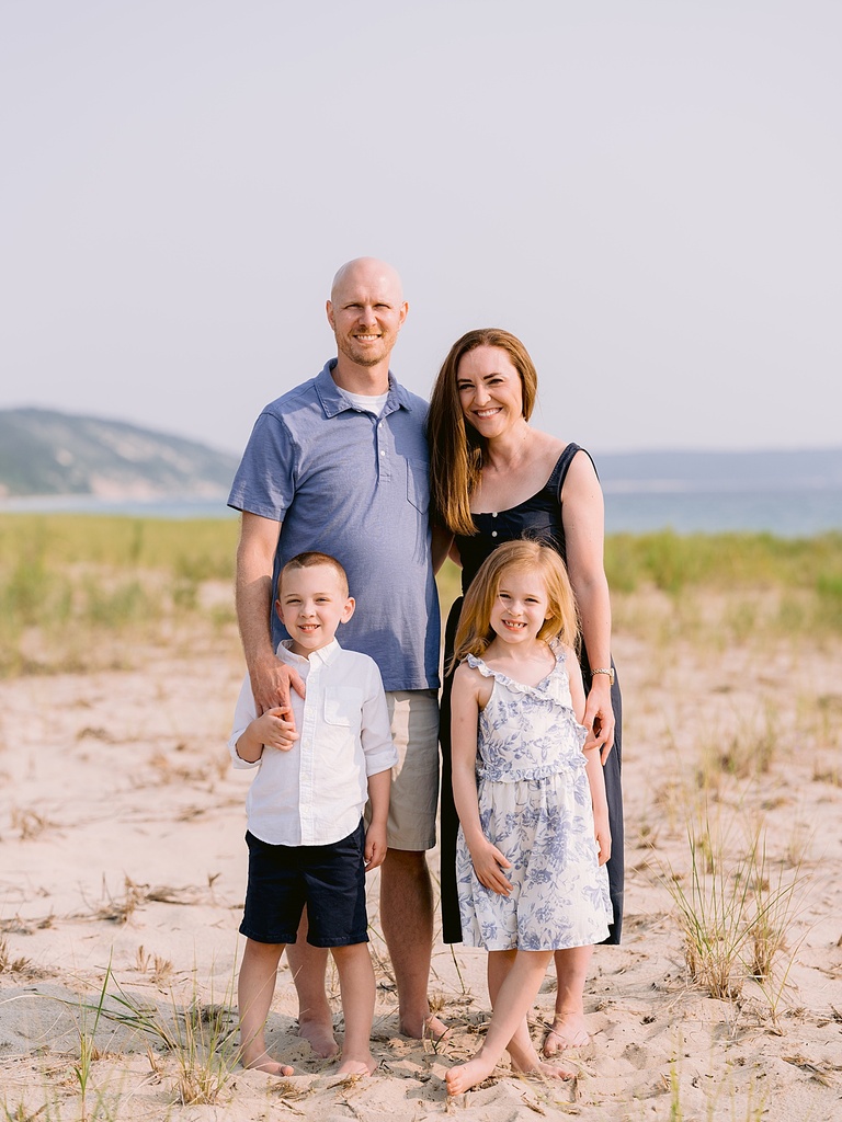 A happy family portrait on a sandy beach on Lake Michigan by Cory Weber