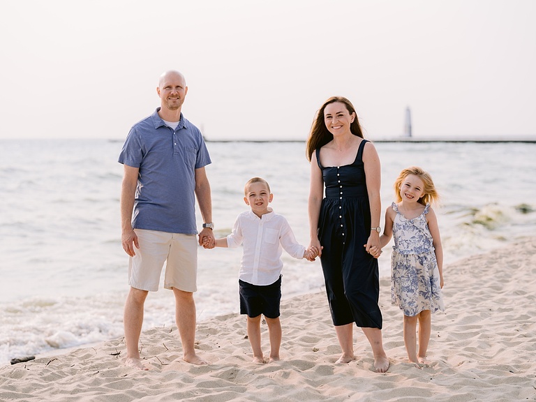 A family holding hands while standing on a beach near the water of Lake Michigan