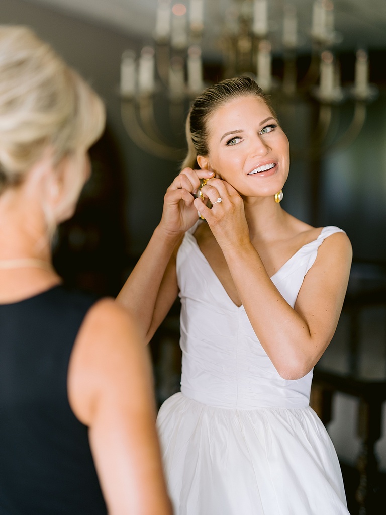 A bride putting on gold Chanel earrings