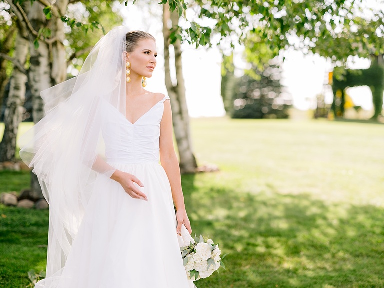 A bride looking at the ceremony area white taking portraits on a sunny summer day in Michigan