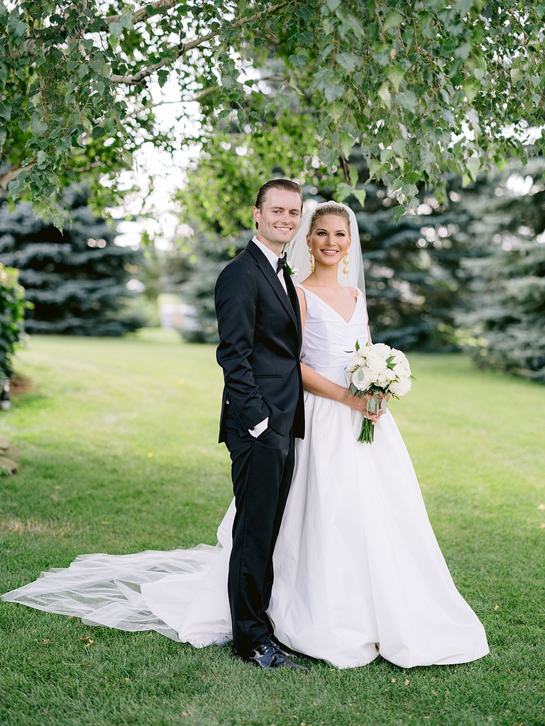 A bride and groom smiling on their wedding day while taking portraits