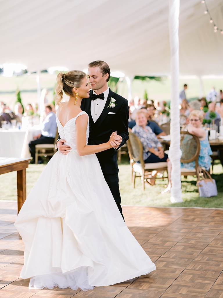 A bride and groom sharing their first dance under a tented wedding