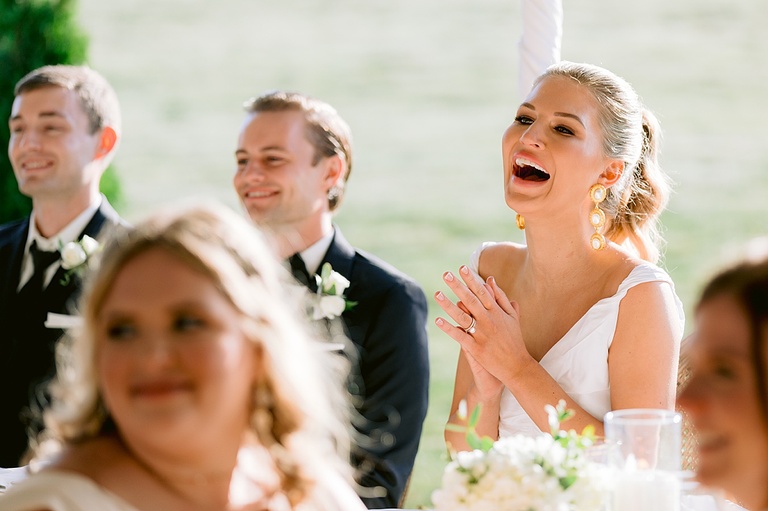 A bride laughing during wedding toasts and speeches