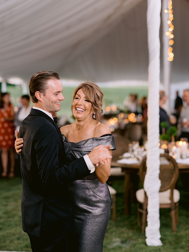A groom dancing with his mother at a tented wedding reception