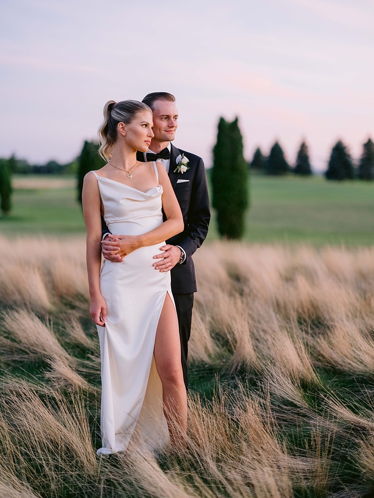 A bride and groom looking at the wedding reception at sunset in lower Michigan