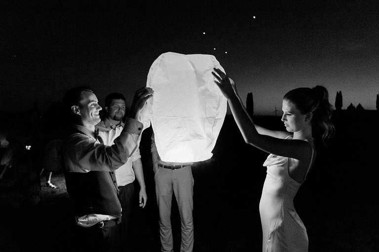 A bride and groom lighting up a lantern to send off