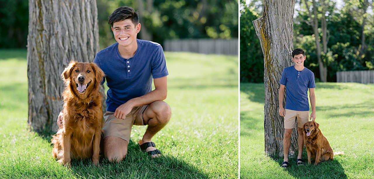 A high school senior poses with his dog on green grass in the sunshine
