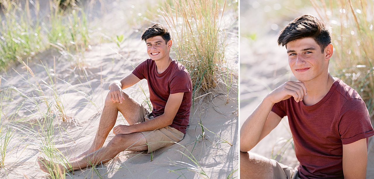 A boy in a red shirt sits in the sand and tall grass on a Northern Michigan beach