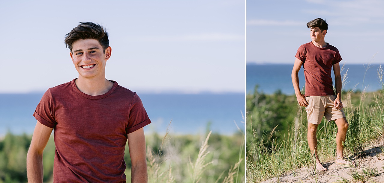 A young man poses for senior photos on a hill with Lake Michigan in the background
