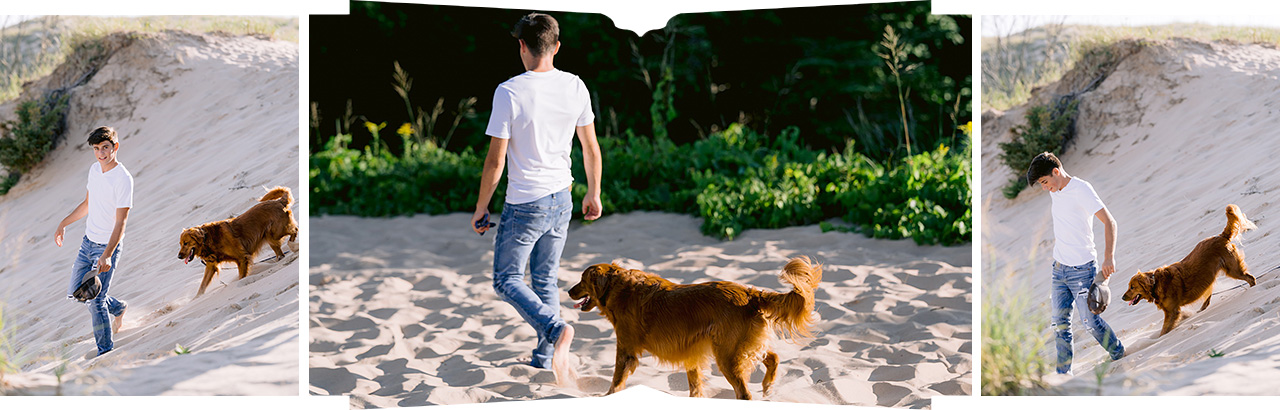 A boy in a white she walks through the sand with his dog in Michigan