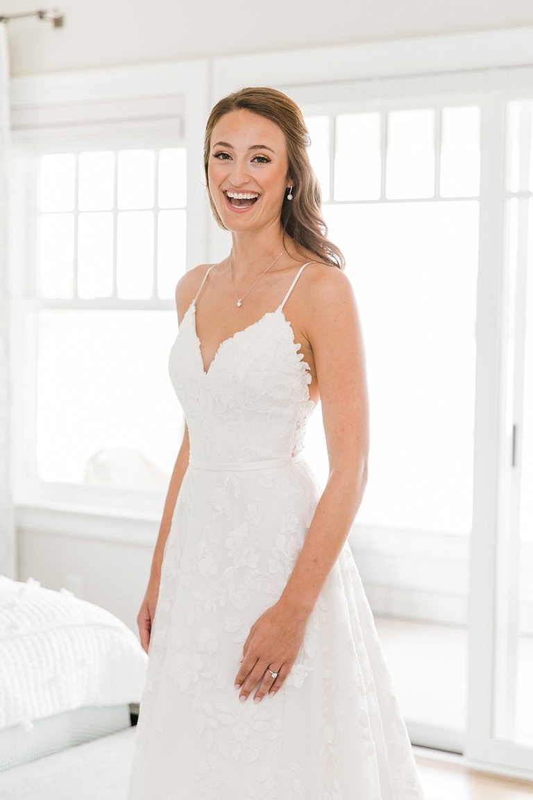 A bride smiling with joy in her wedding dress before going to the church to get married